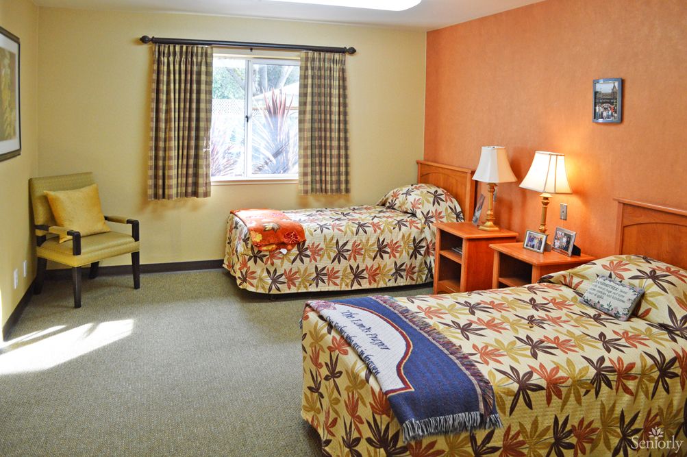 A cozy hotel room with twin beds and a window view.