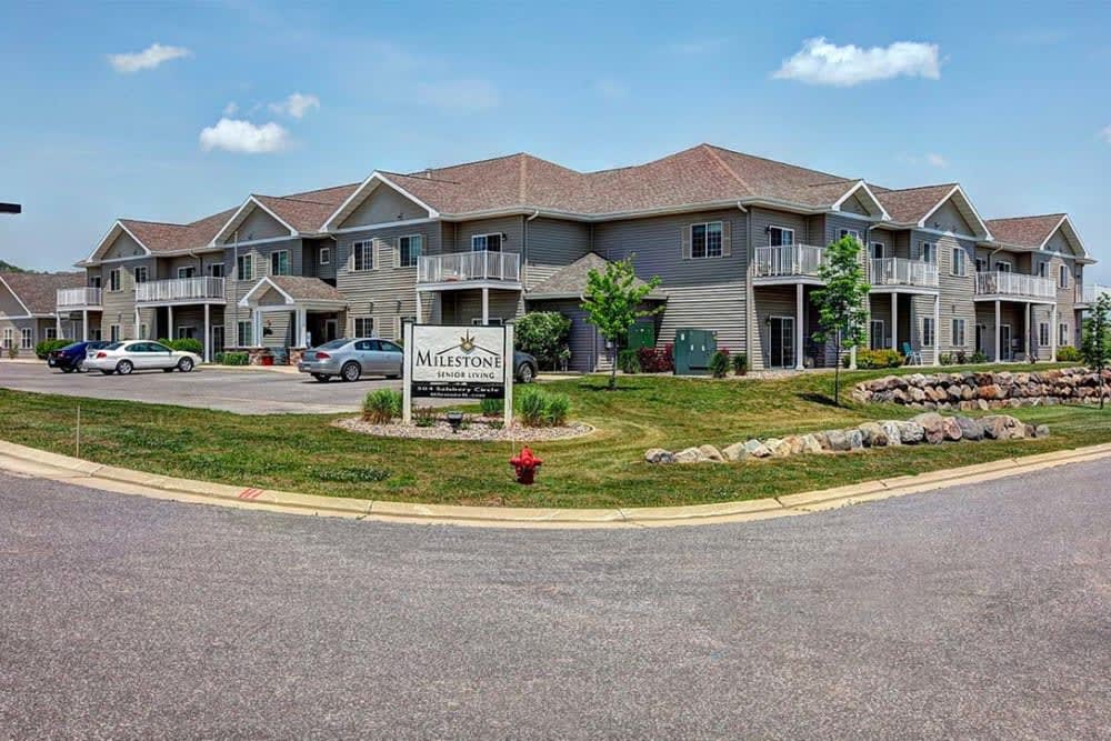 A modern apartment building with balconies and a well-maintained lawn under a clear blue sky.