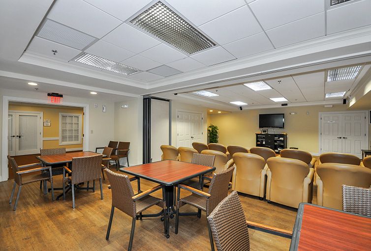 A well-arranged meeting room with tables, chairs, and a large screen for presentations.