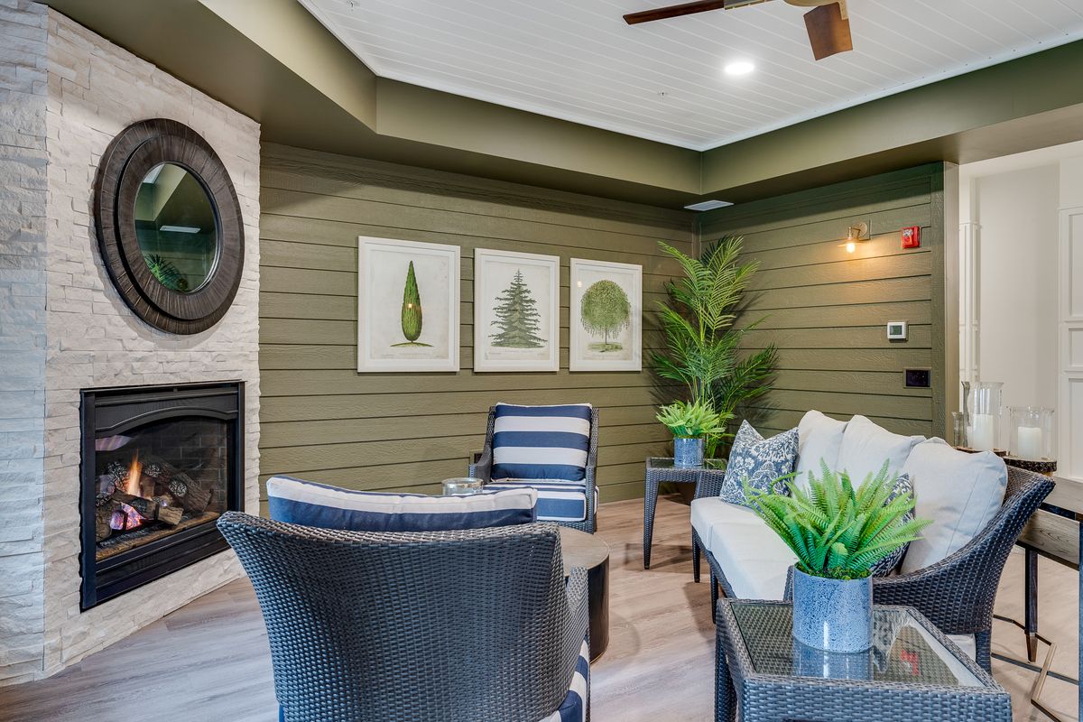 A modern living room featuring a fireplace, artwork, and comfortable seating with plants adding a touch of greenery.