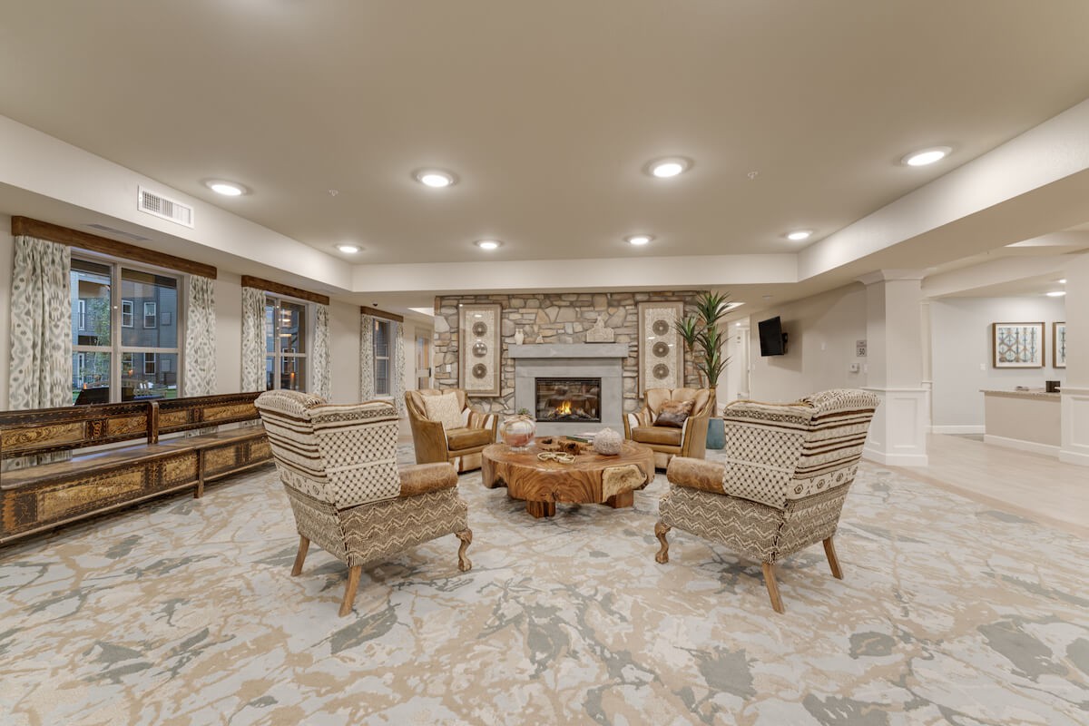 A cozy living room with a central fireplace surrounded by comfortable seating and warm decor.
