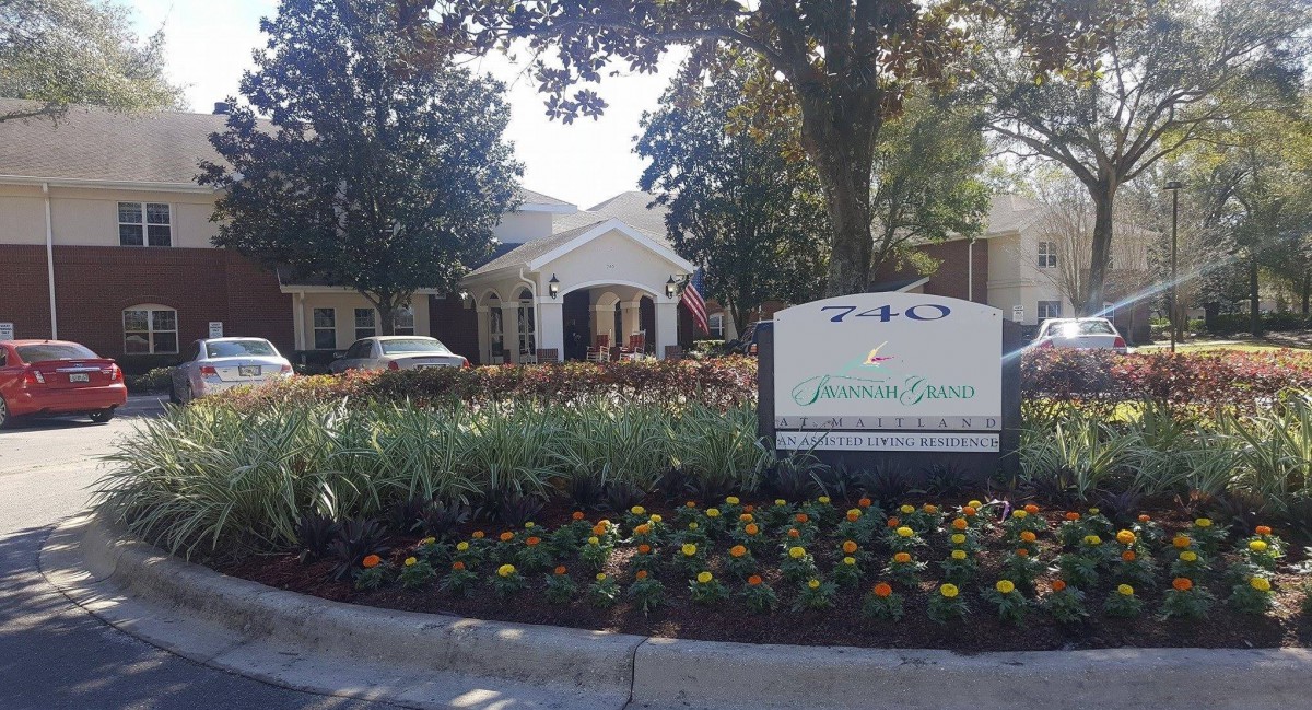 A residential building with a landscaped entrance and a prominent sign.