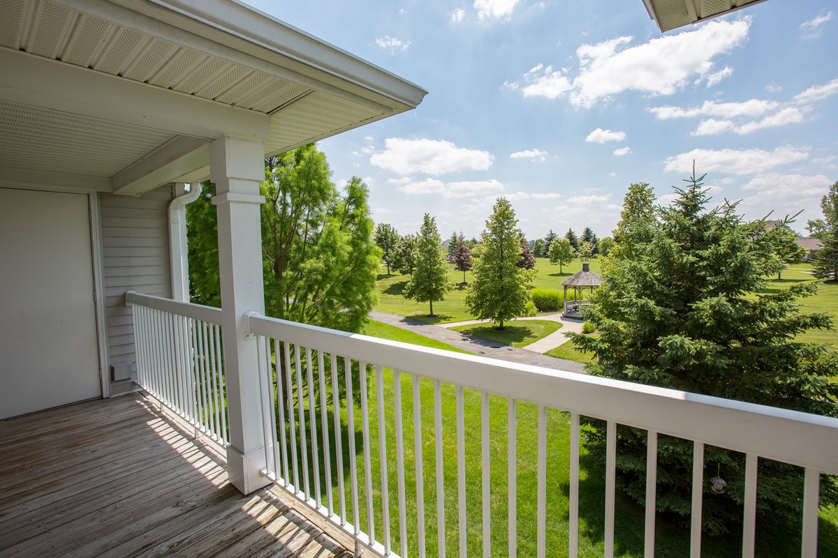 A scenic view from a balcony overlooking a lush, green park on a sunny day.