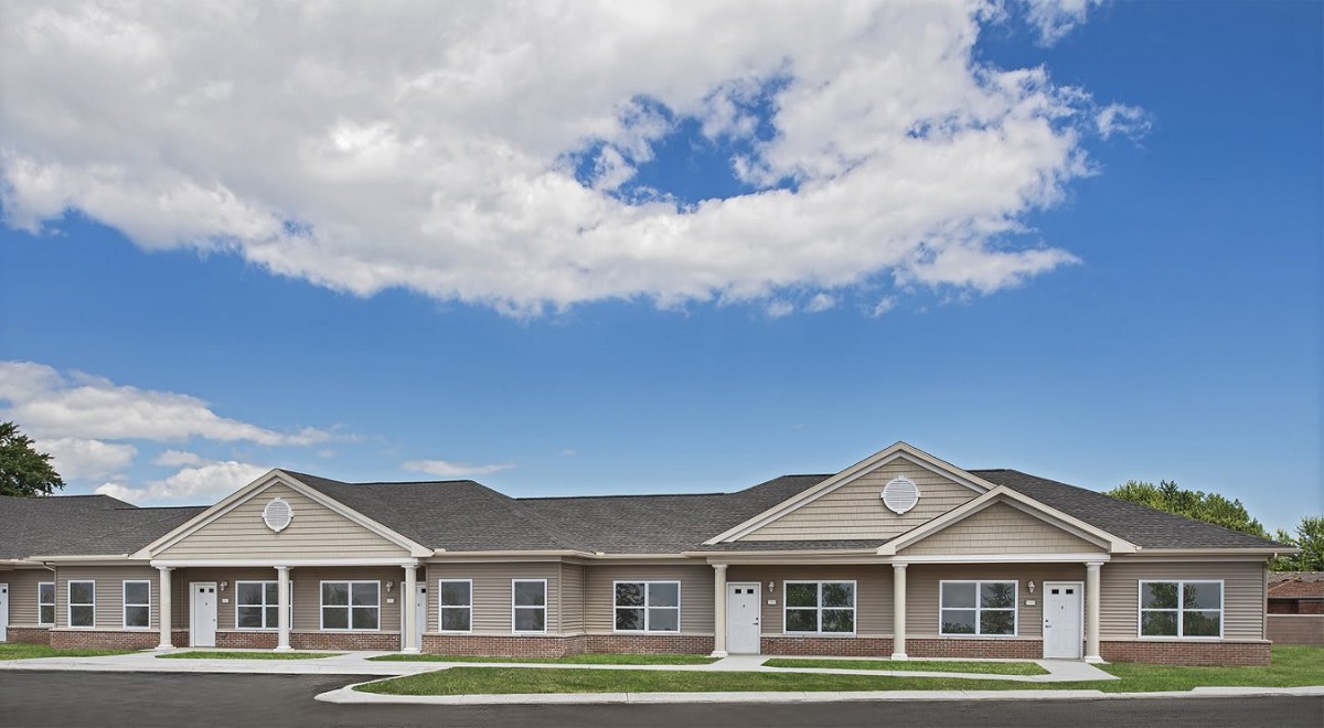 A single-story residential building under a partly cloudy sky.