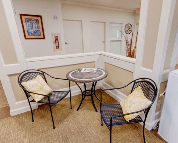 A cozy indoor seating area with two cushioned chairs and a small round table.