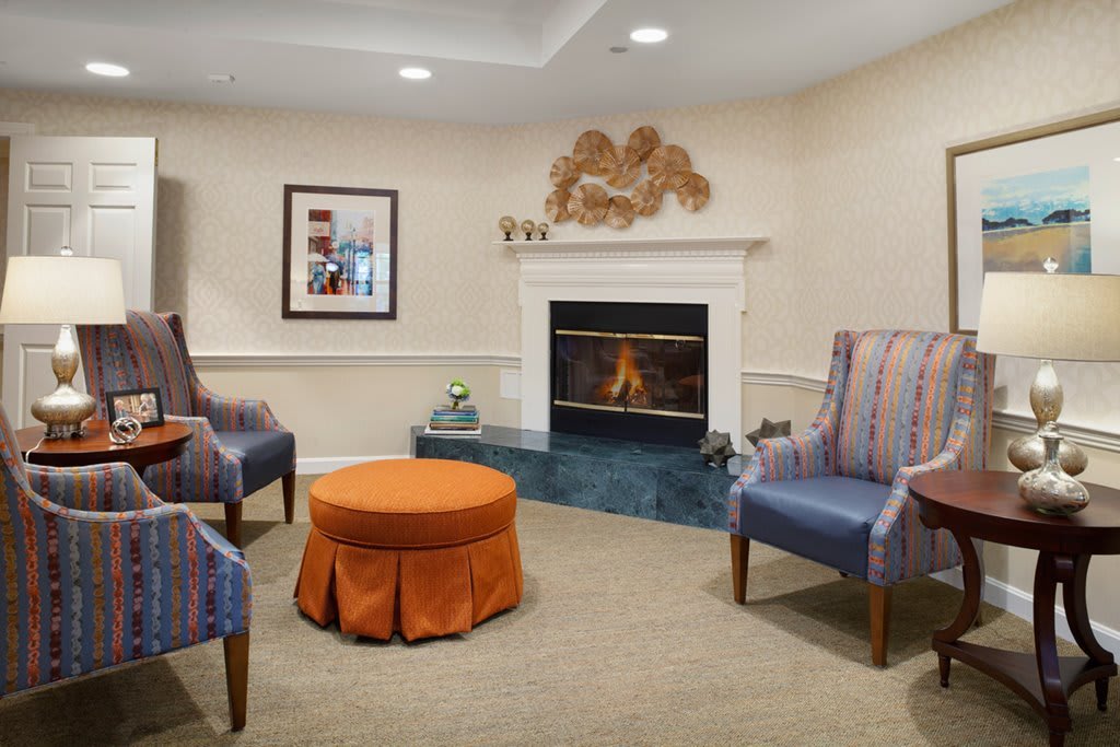A cozy living room featuring a fireplace, armchairs, and a central coffee table.