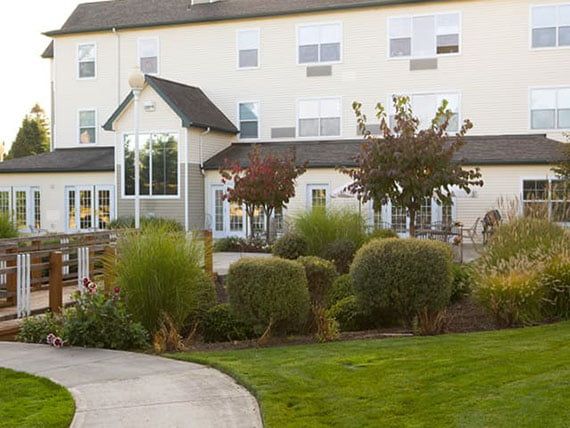 A landscaped area with bushes and trees in front of a multi-story building.