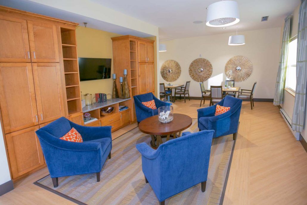 A modern living room with blue chairs and wooden furniture, featuring a television and stylish decor.