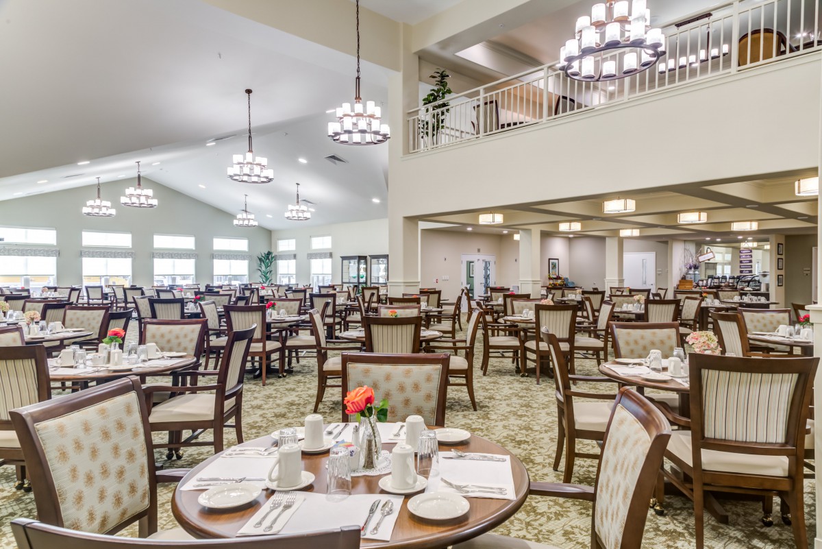 A spacious dining room with neatly arranged tables and elegant chandeliers.