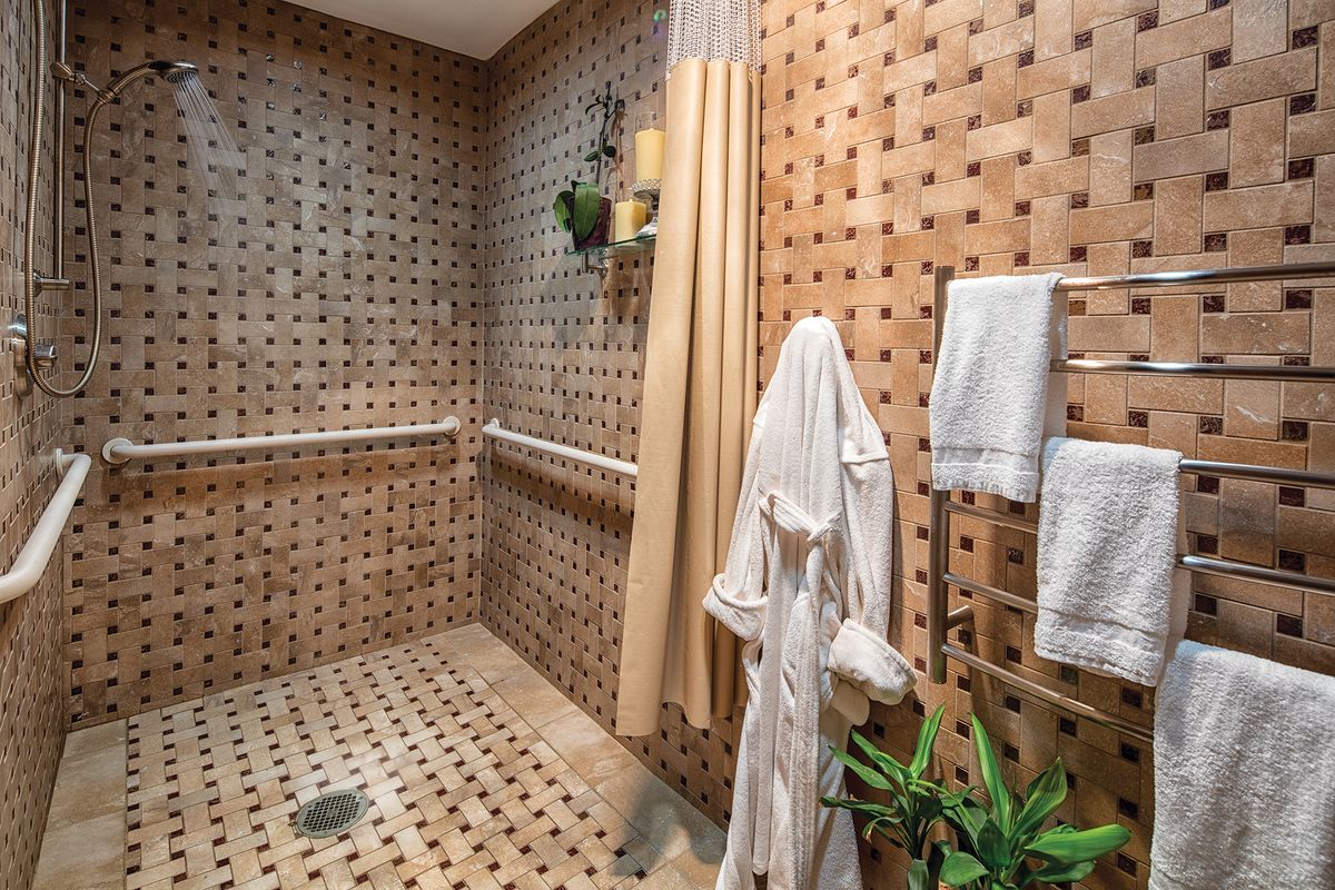 A stylish bathroom features patterned tiles, a cozy robe, and lush plants for a relaxing ambiance.
