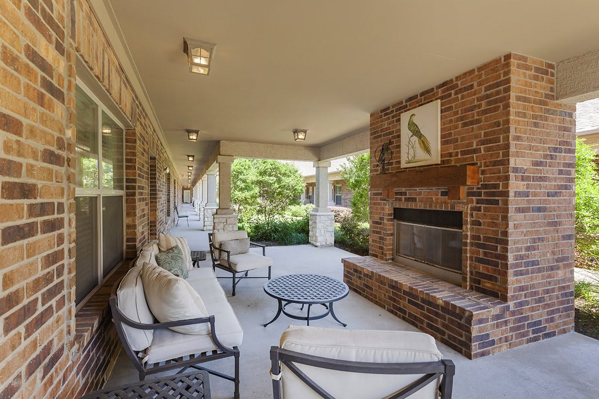 A cozy outdoor patio featuring a brick fireplace and comfortable seating, overlooking a lush garden.