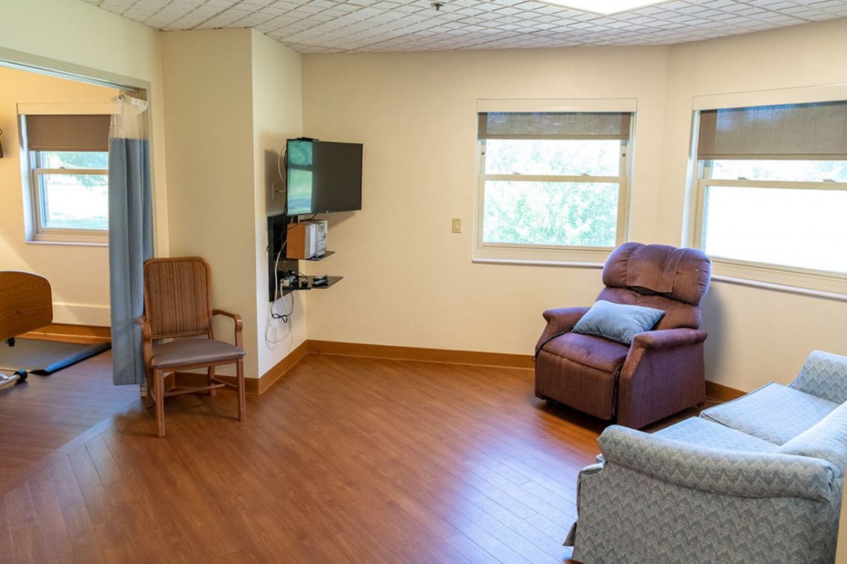 A cozy living room with a recliner, chair, television, and a window with natural light.