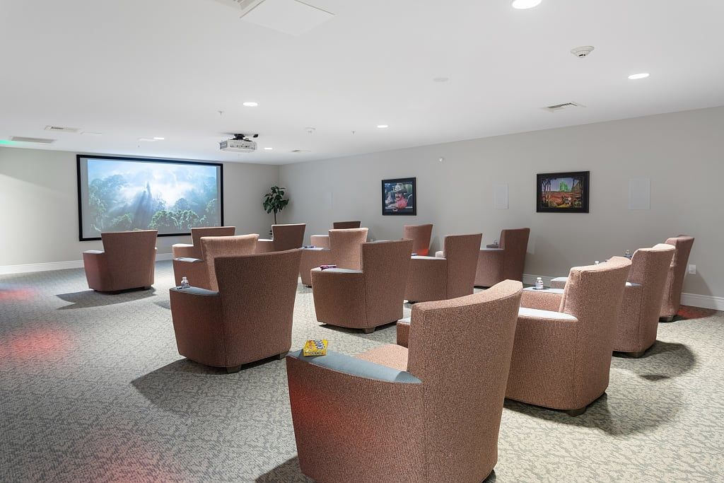 A modern conference room with arranged seating and a large projector screen.