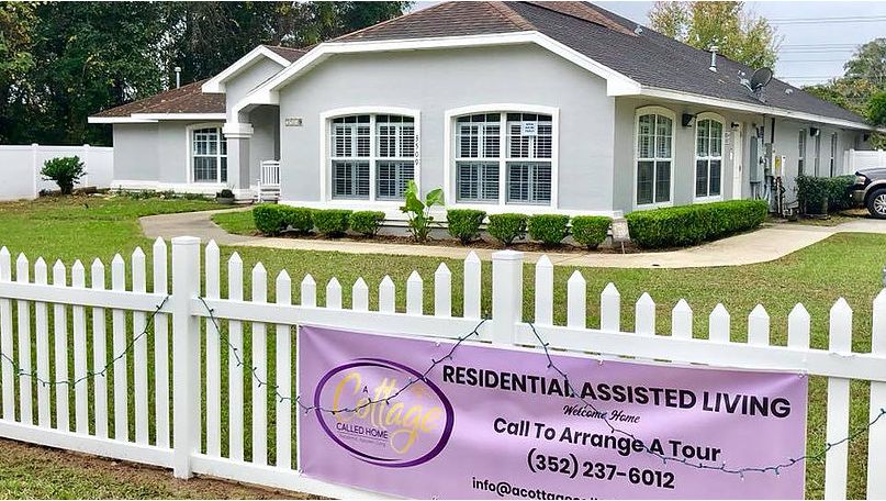 Residential assisted living facility with a sign on the fence providing contact information for tours.