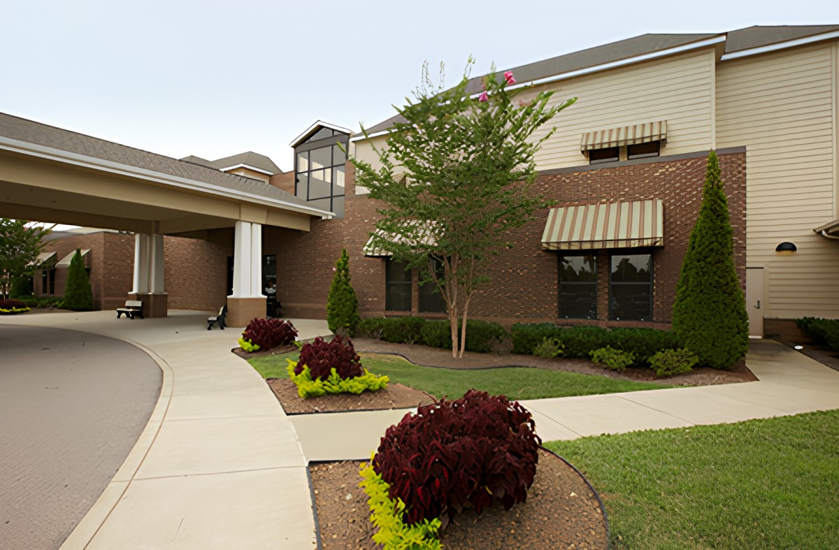 A modern brick building with landscaped gardens and a walkway.
