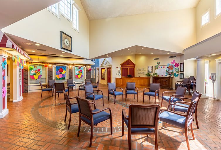 A spacious and bright lobby with chairs arranged in a circle, featuring colorful artwork on the walls.