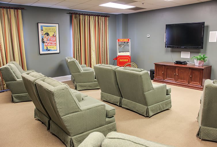 A cozy home theater setup with green chairs, a popcorn machine, and a TV.