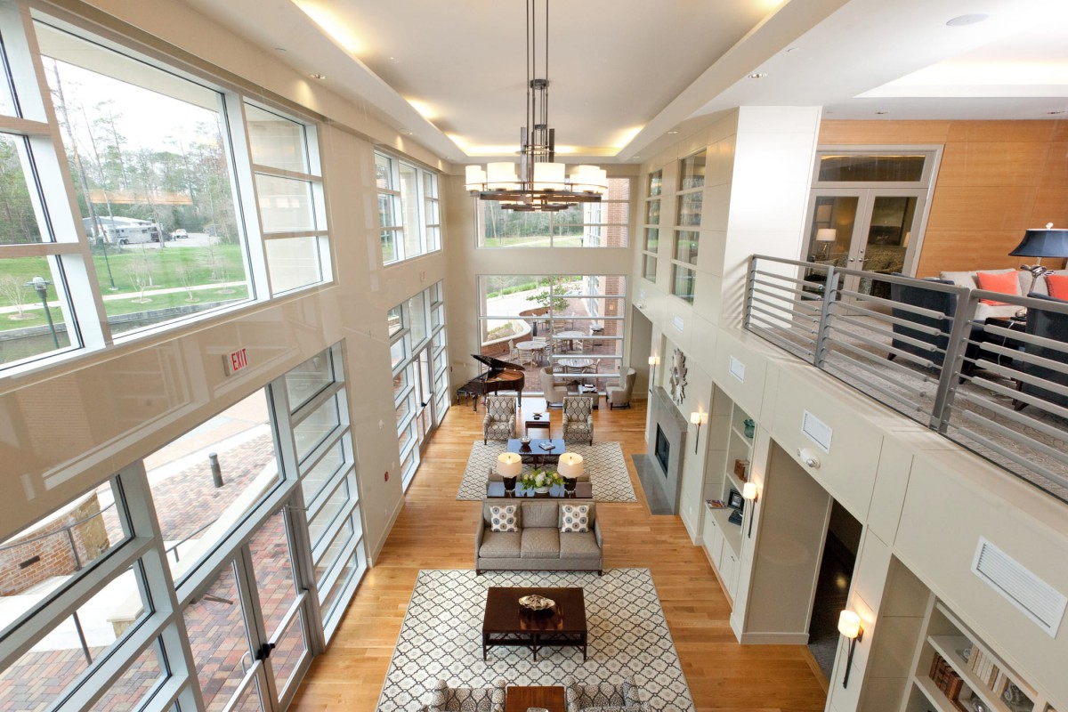 A modern living room with large windows and ample natural light, featuring stylish furniture in an open space.
