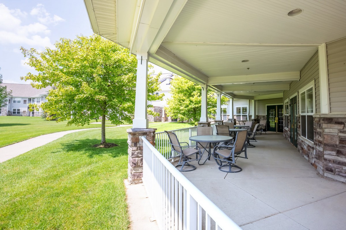 A spacious patio with outdoor seating overlooking a green lawn and trees.