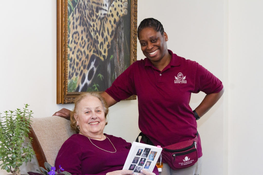 A caregiver and a senior woman smiling together indoors.