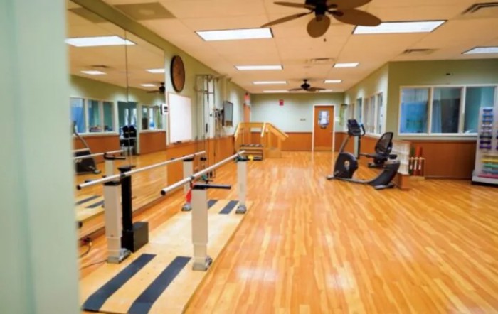 A well-equipped fitness room with exercise machines and mirrors lining the walls.