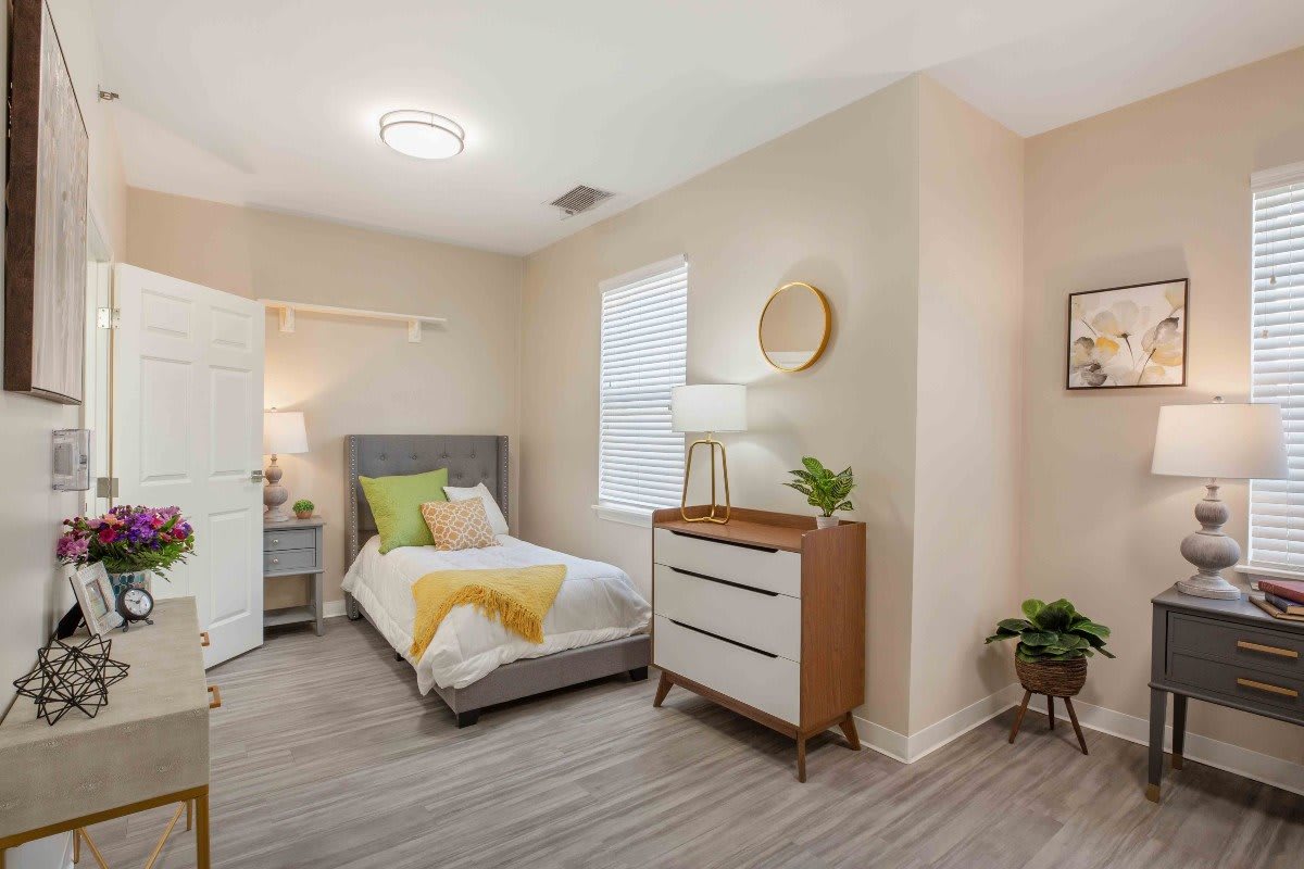 A modern and minimalist bedroom with a cozy bed, dresser, and decorative elements.