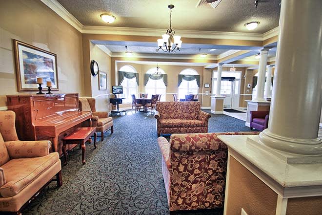 A cozy lounge area with elegant furnishings, including a piano, sofas, and a chandelier.