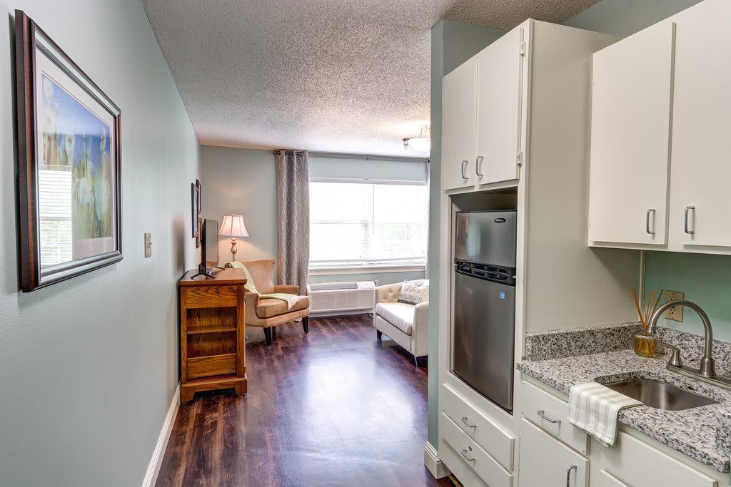 A modern apartment interior featuring a compact kitchen and cozy living area with wood flooring.