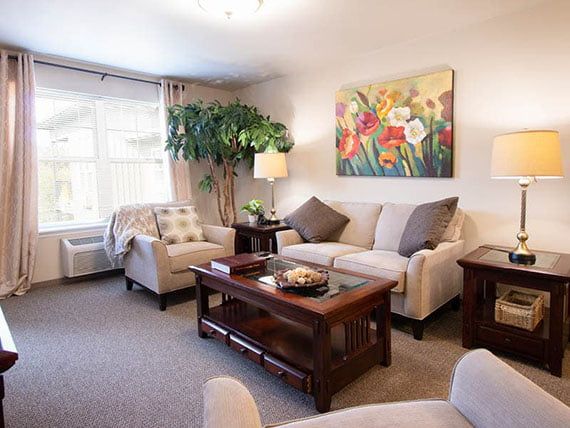 A cozy living room featuring a sofa set, coffee table, and colorful painting.
