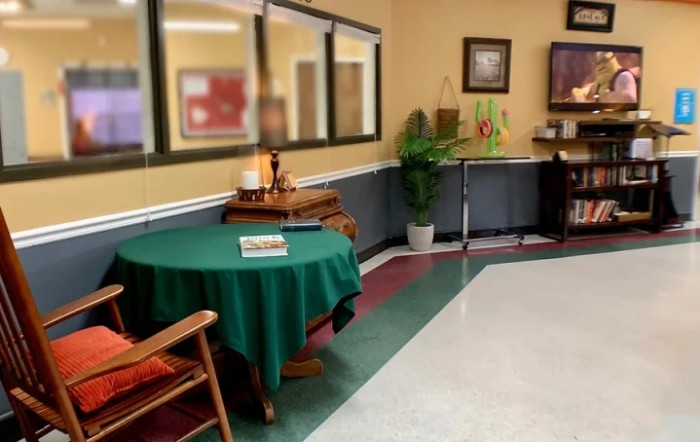 A cozy waiting area with a green tablecloth on the table, chairs, and wall decorations.