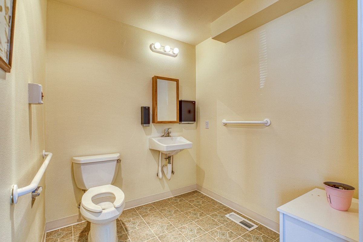 A simple bathroom with a toilet, sink, mirror, and towel rack.