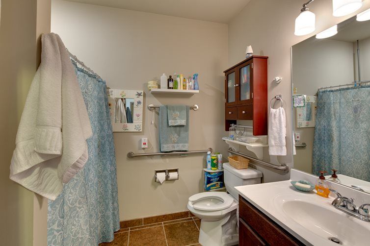 A well-organized bathroom with a toilet, sink, mirror, and shower curtain.