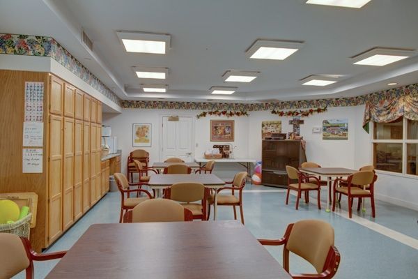 A communal room with tables and chairs, decorated with wall art and garland.