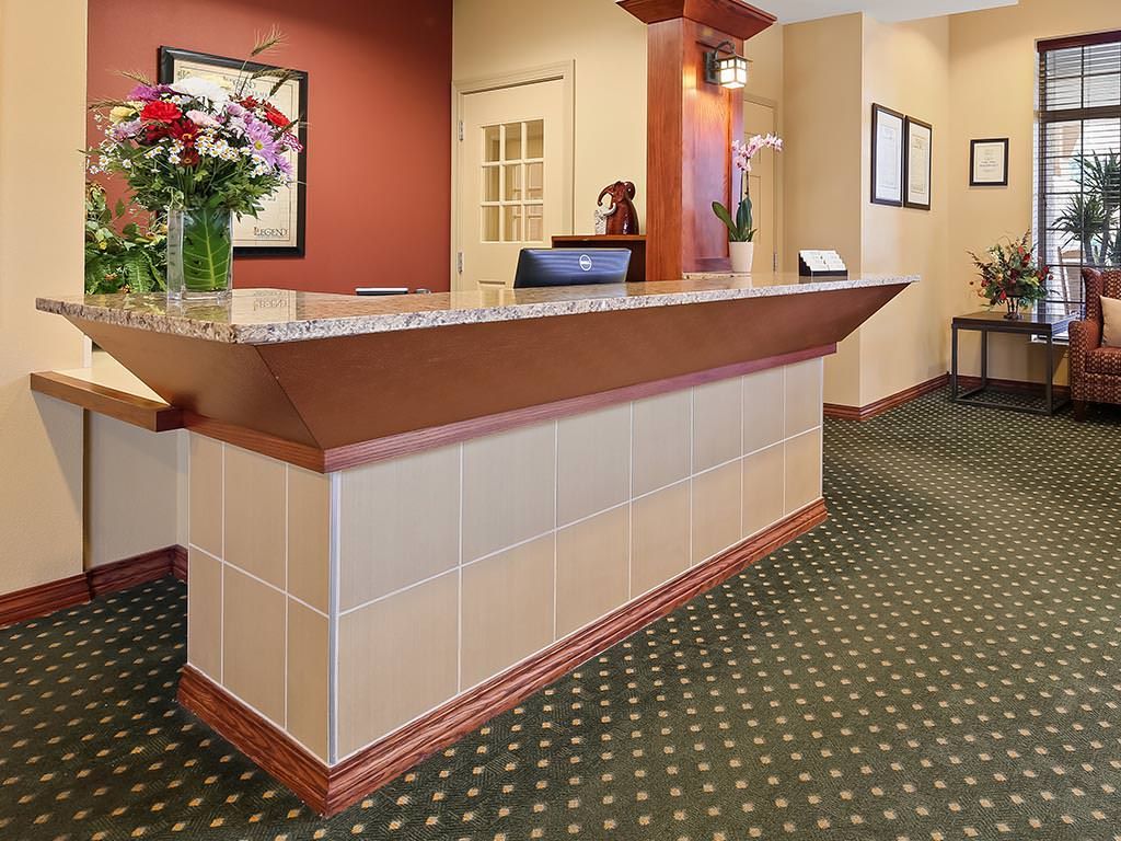 A neat and welcoming hotel reception area with a counter and floral arrangement.