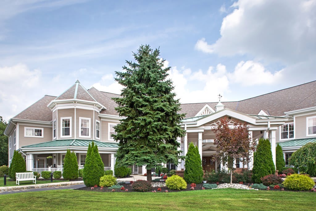 A picturesque mansion surrounded by lush greenery and a clear sky.