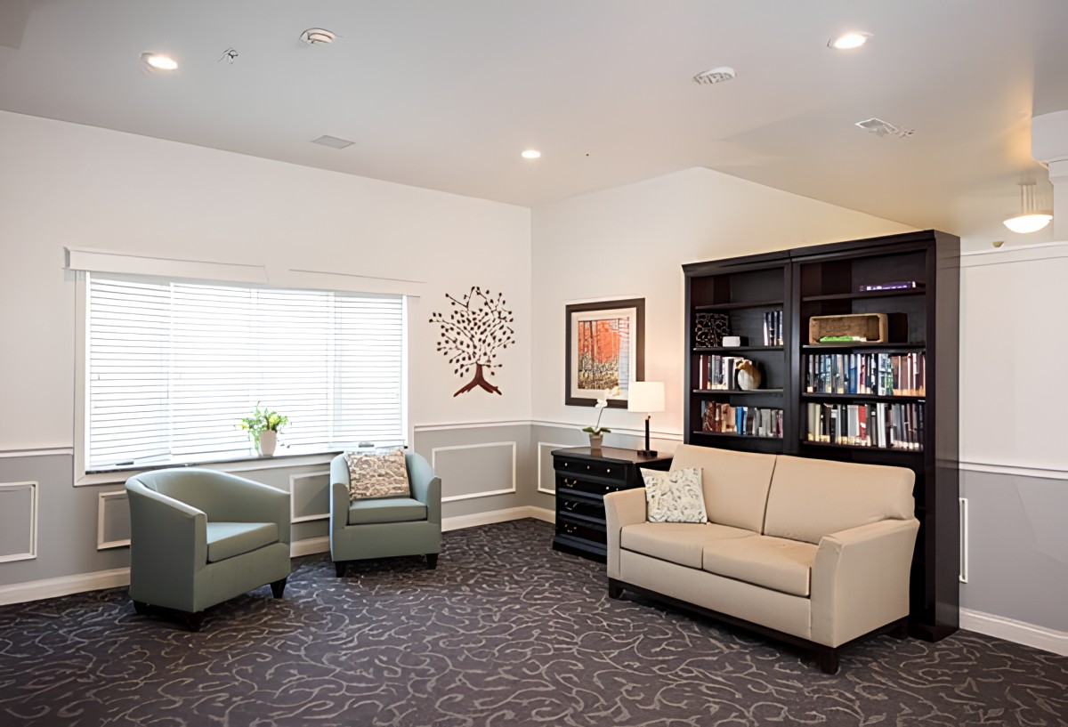 A cozy living room with a sofa, armchairs, a bookshelf, and decorative wall art.
