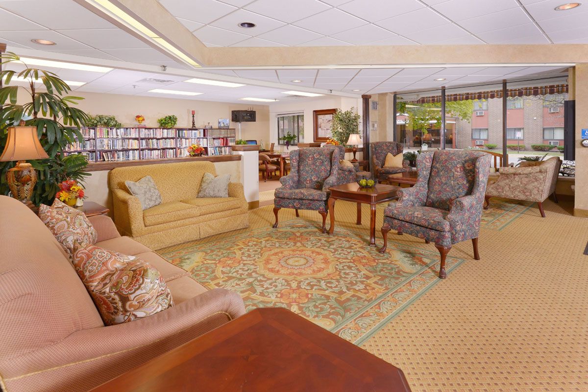 A cozy living room with comfortable seating and an array of books on shelves.