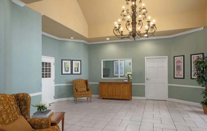 A spacious lobby with a chandelier, seating, and a reception desk.