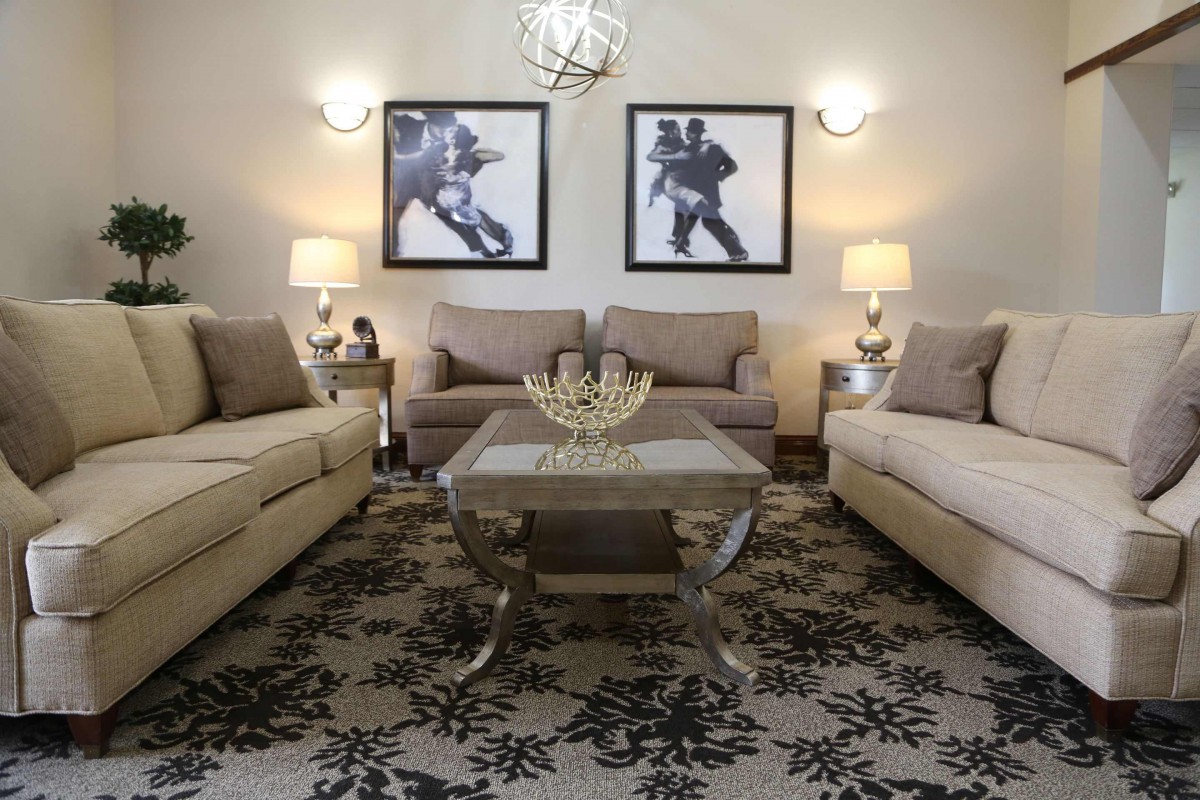 A stylish living room with two sofas, a central coffee table, framed artwork, and elegant lighting.