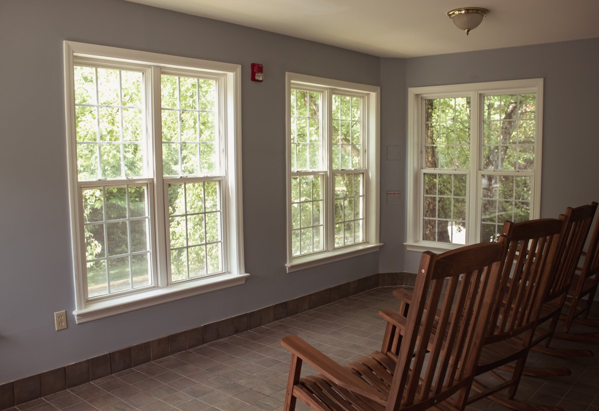 A cozy sunroom with large windows allowing natural light to fill the space, featuring a comfortable rocking chair.
