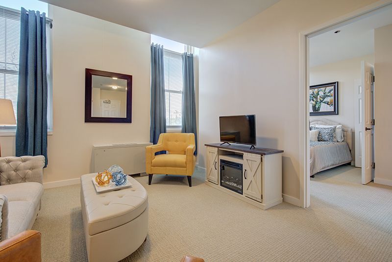 A cozy living room with a yellow armchair, television, and a decorative mirror.