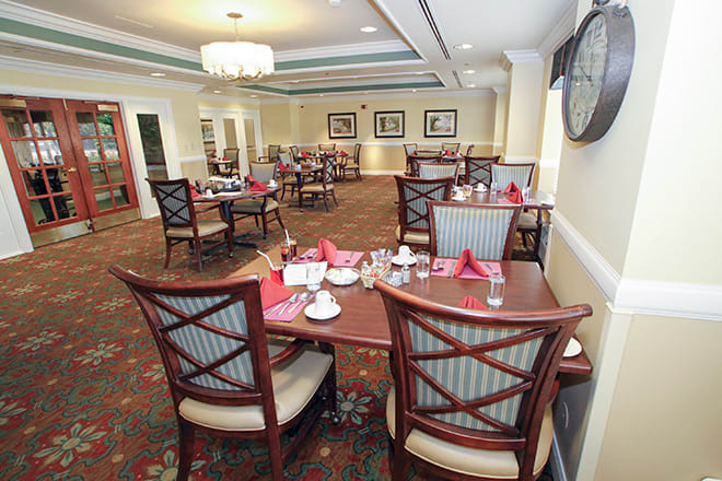 A well-lit dining area with neatly arranged tables and chairs, featuring a formal setting.