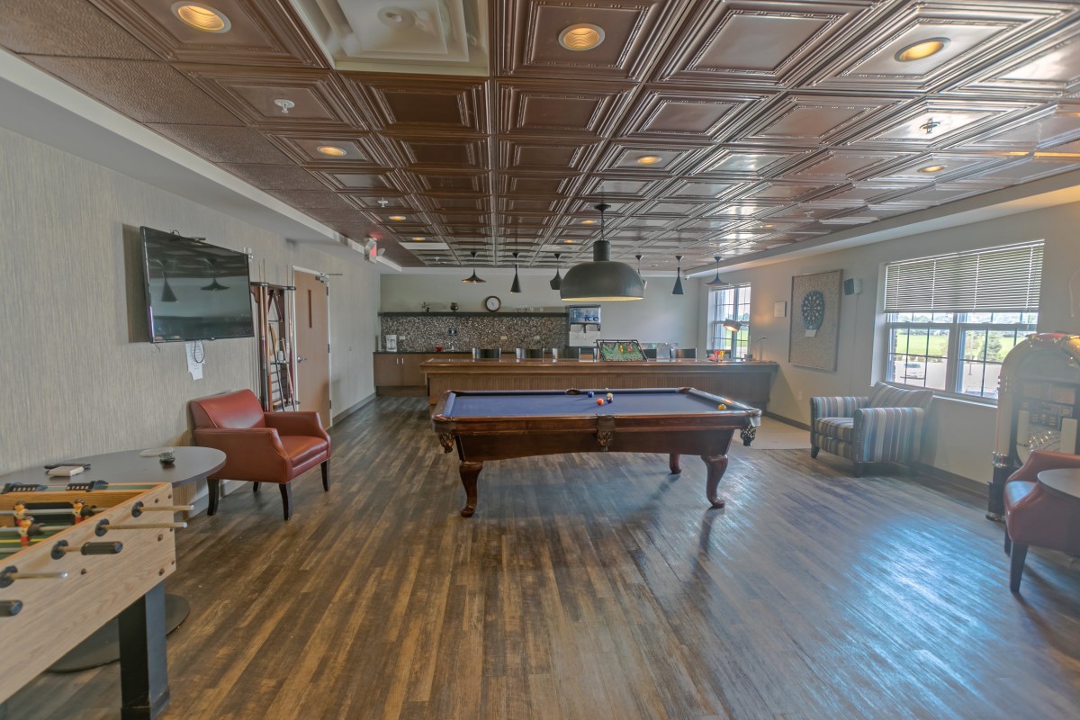 A stylish game room featuring a pool table and dining area with elegant wood flooring.