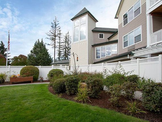 A well-maintained garden with shrubs and a lush lawn beside a modern building.