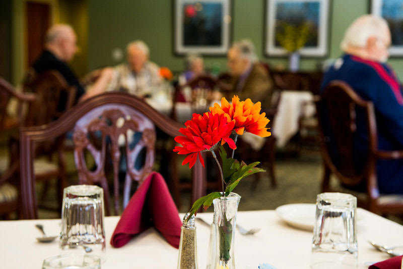 A beautifully set table in a restaurant, featuring vibrant flowers and elegant glassware.