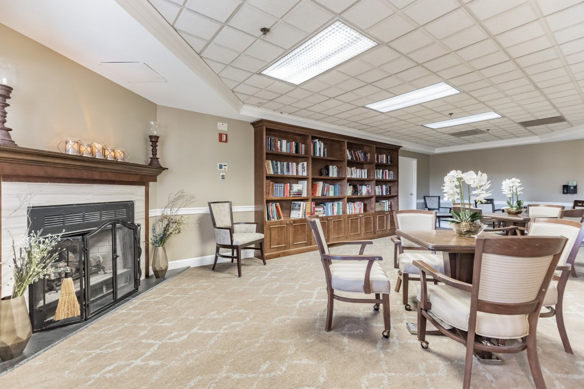 A cozy library space with a fireplace, bookshelves, and seating for reading.