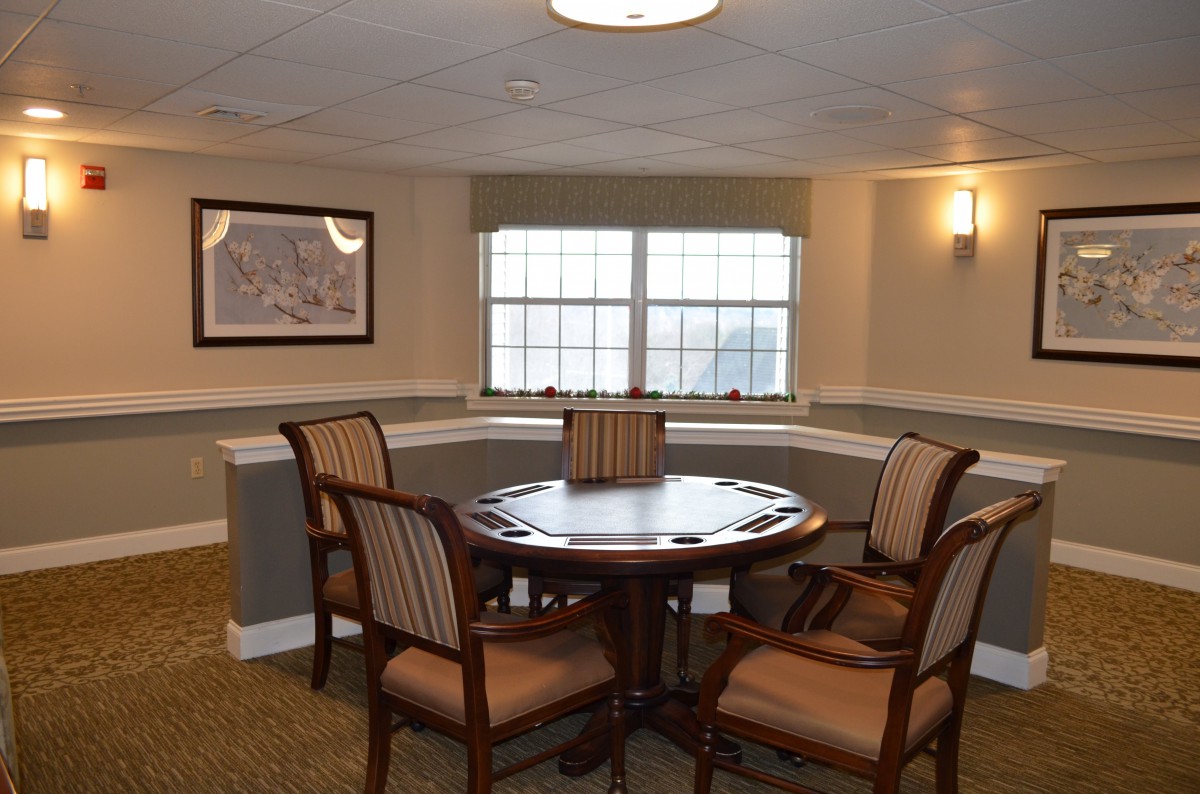 A cozy dining area with a round wooden table surrounded by four chairs, set near a window with natural light.