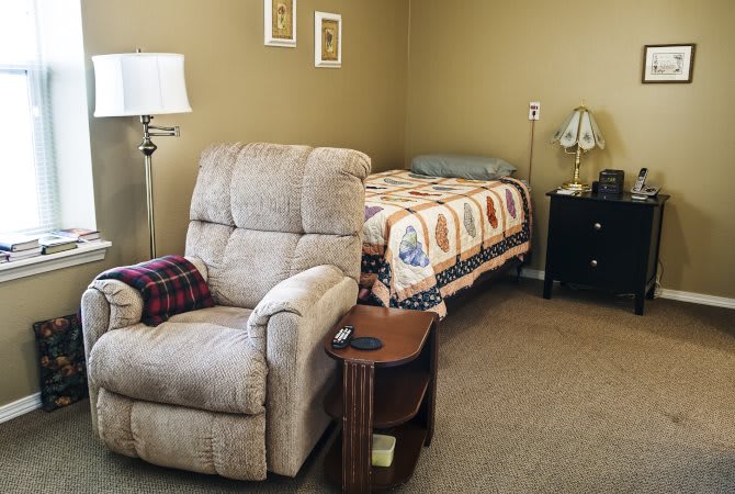A cozy bedroom with an armchair, bed, and nightstand.