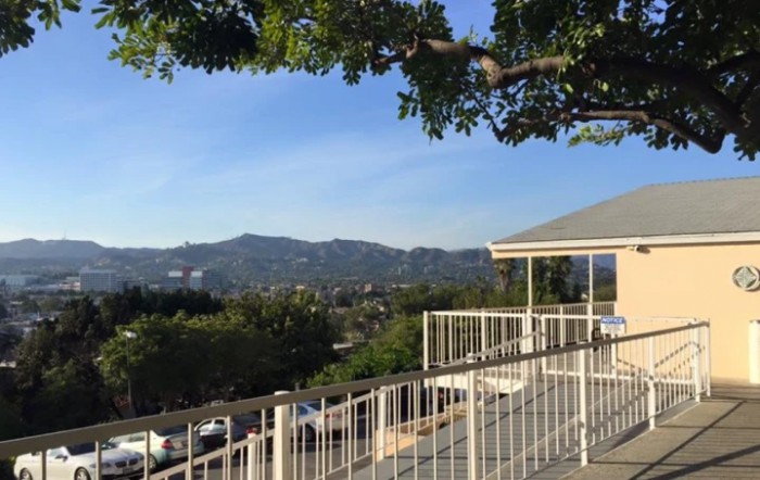A scenic view of mountains and trees from a balcony with a railing.