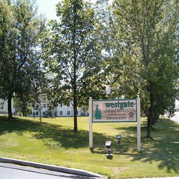 A park area with a sign reading 'Westside' surrounded by trees and grass.